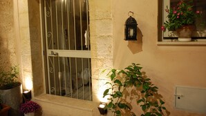 A stone wall with a barred window, a lantern, and potted plants. - 2 BR apt., gated courtyard, right by ocean & sites (Siracusa)