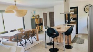 Een moderne keuken met een eethoek, met een grote tafel, stoelen en een koelkast.