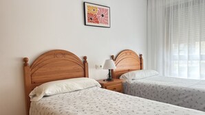 Et dobbeltværelse med to trægavle, et natbord med lampe, og et sengetæppe med blomstermønster.