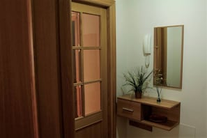 A wooden door with a glass panel, a wooden vanity with a mirror, a telephone, and a plant.