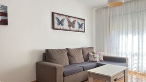 Una sala de estar con un sofá, una mesa de centro y un cuadro de mariposas en la pared.