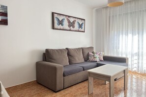 A living room with a sofa, a coffee table, and a painting of butterflies on the wall. - Disconnectaengalicia La Perla Superior, swimming pool and parking (Portonovo)