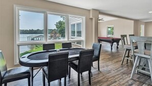 A spacious room with a pool table, a dining area with a large window offering a view of a lake and trees, and a ceiling fan. - 4 Bedrooms, 1 Flex Room, 3½ Bathrooms!  Pet Friendly! Many Recent Updates! Sits Close to the Water! (Moneta)