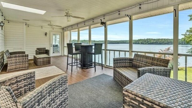 A covered outdoor seating area with wicker furniture, a table, and chairs, overlooking a lake. - 4 Bedrooms, 1 Flex Room, 3½ Bathrooms!  Pet Friendly! Many Recent Updates! Sits Close to the Water! (Moneta)