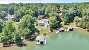 A lakeside property with multiple houses, a dock, and a small boat. - 4 Bedrooms, 1 Flex Room, 3½ Bathrooms!  Pet Friendly! Many Recent Updates! Sits Close to the Water! (Moneta)