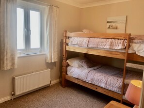 A bunk bed room with a window, radiator, and a painting on the wall. - Wheal Kendall (St Austell)