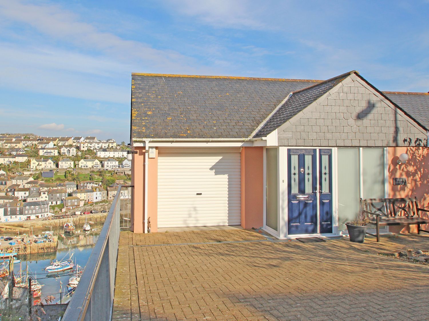 A residential building with a garage, a balcony, and a view of a marina with boats.