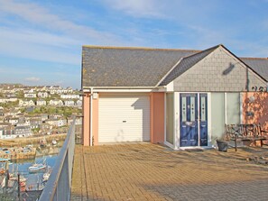 A residential building with a garage, a balcony, and a view of a marina with boats. - Wheal Kendall (St Austell)