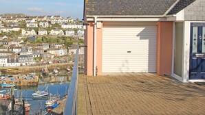A coastal building with a garage door, overlooking a marina with boats. - Wheal Kendall (St Austell)