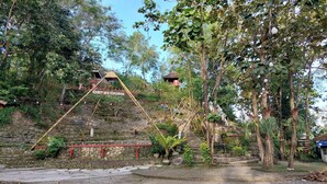 A park with a wooden swing set, stone steps, and a small building labeled "DEMI GUMI". - Camping Ground Gunung Mijil Hils (Bantul)
