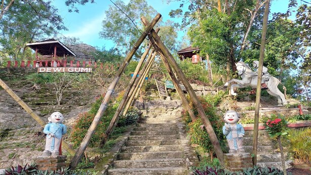 A staircase with a wooden structure at the top, surrounded by greenery and a statue. - Camping Ground Gunung Mijil Hils (Bantul)