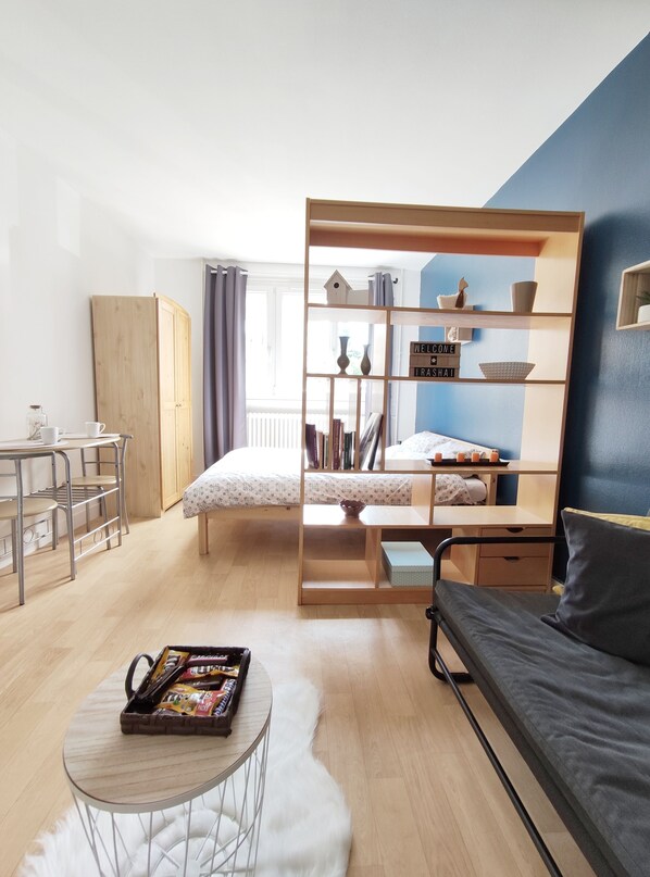 Une chambre à coucher de taille modeste, comprenant un lit, un bureau, une bibliothèque et un canapé.