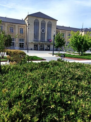 A building with a clock, a sign reading "GARE DE CHARTRES," and a well-maintained garden in the foreground.