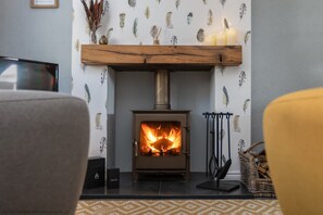 A cozy living room with a fireplace, a television, and a patterned wall.