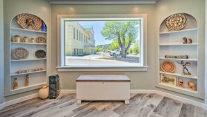Une pièce dotée d’une grande fenêtre, d’un plancher en bois et d’étagères ornées d’objets décoratifs.