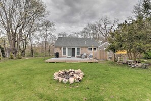 A house with a deck, a fire pit, and a backyard with trees.