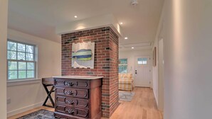 Una habitación con chimenea de ladrillo, cómoda de madera y una ventana.