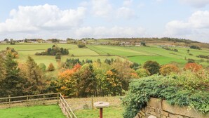 A rural landscape with fields, trees, and a stone wall. - Bronte Barn (Keighley)