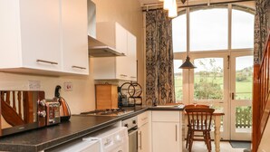 A compact kitchen with a washing machine, a toaster, and a dining area with a view of the outdoors. - Bronte Barn (Keighley)