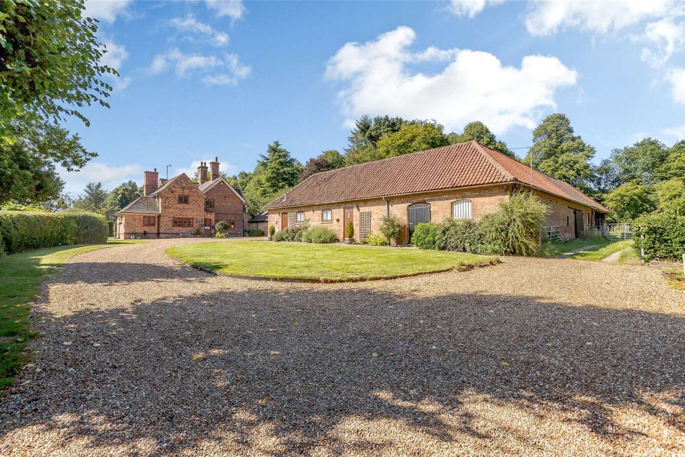 A large stone house with a gravel driveway and a well-maintained lawn.