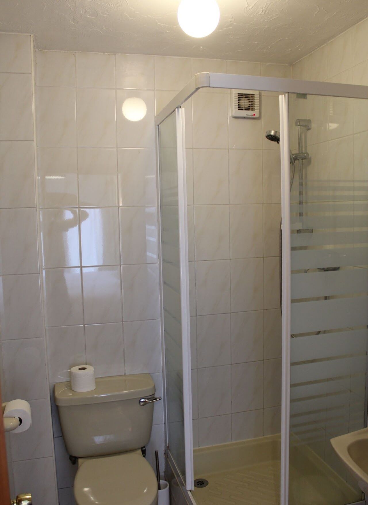 A bathroom with a toilet, a shower enclosure, and a sink.