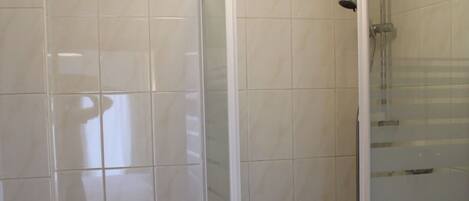 A bathroom with a toilet, a shower enclosure, and a sink.