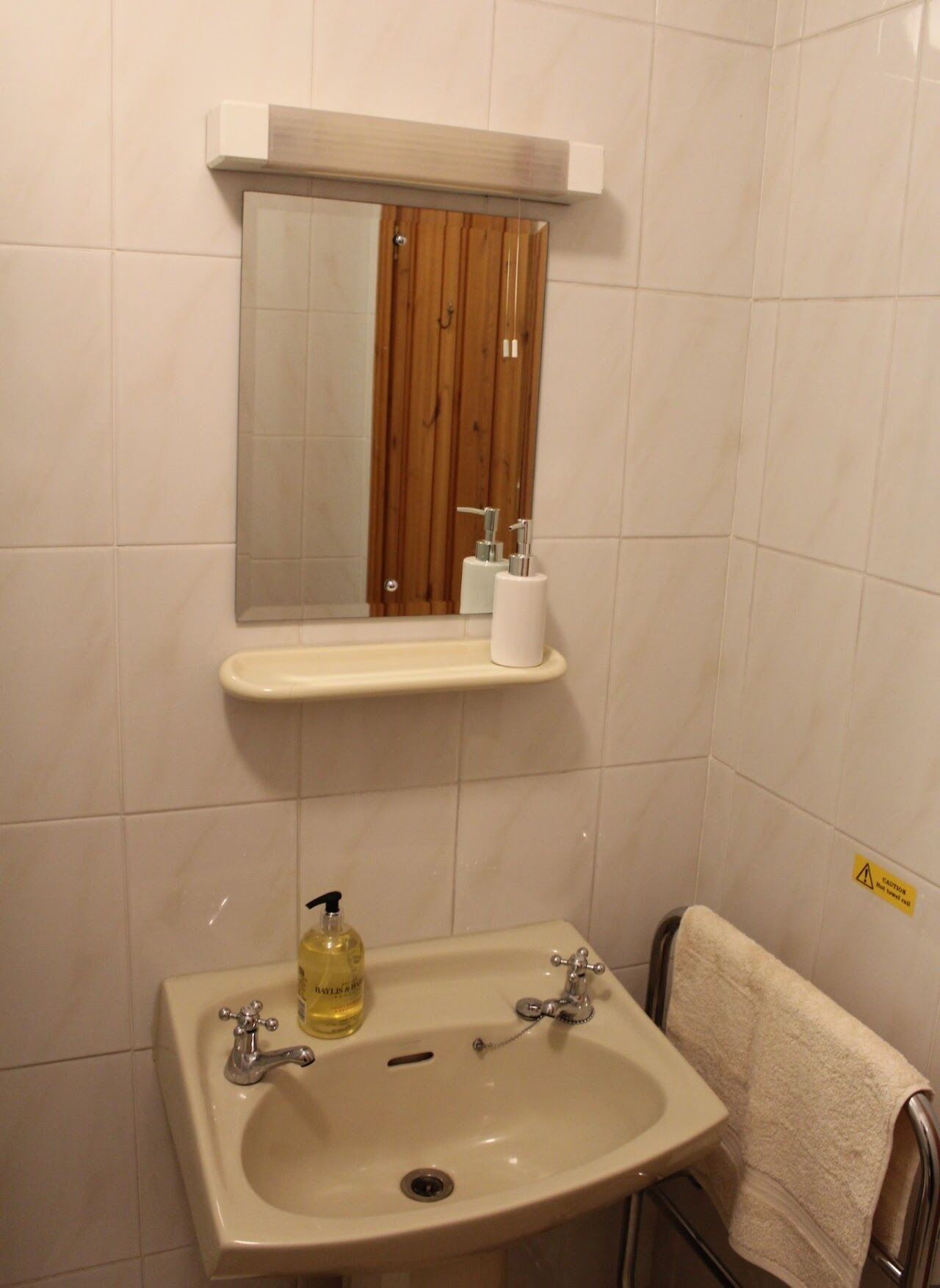 Un baño con lavamanos, espejo y puerta de madera.