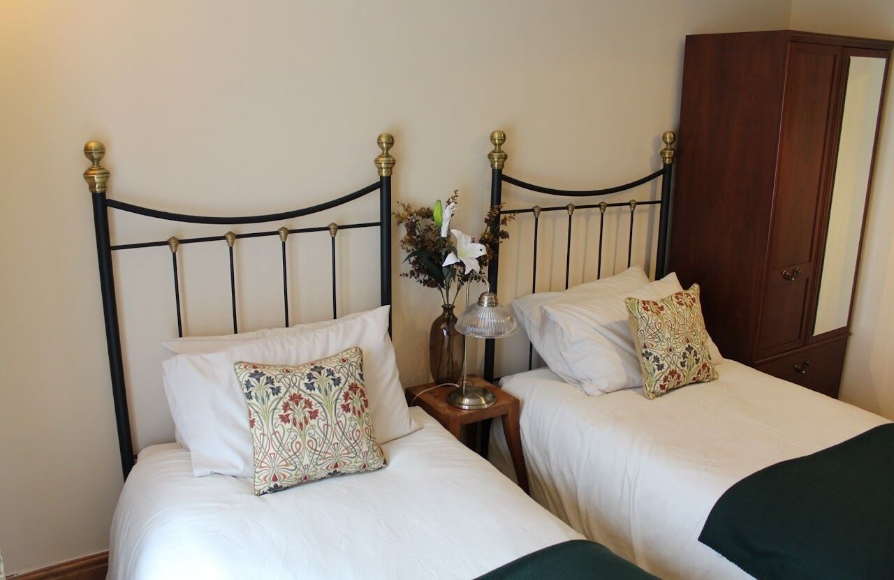 A double bed with a metal headboard, a bedside table with a lamp, and a mirror cabinet.