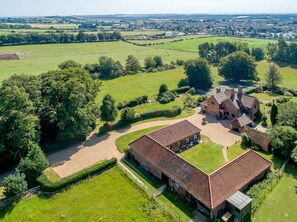 An aerial view of a large estate with multiple buildings, expansive green fields, and a well-maintained garden.