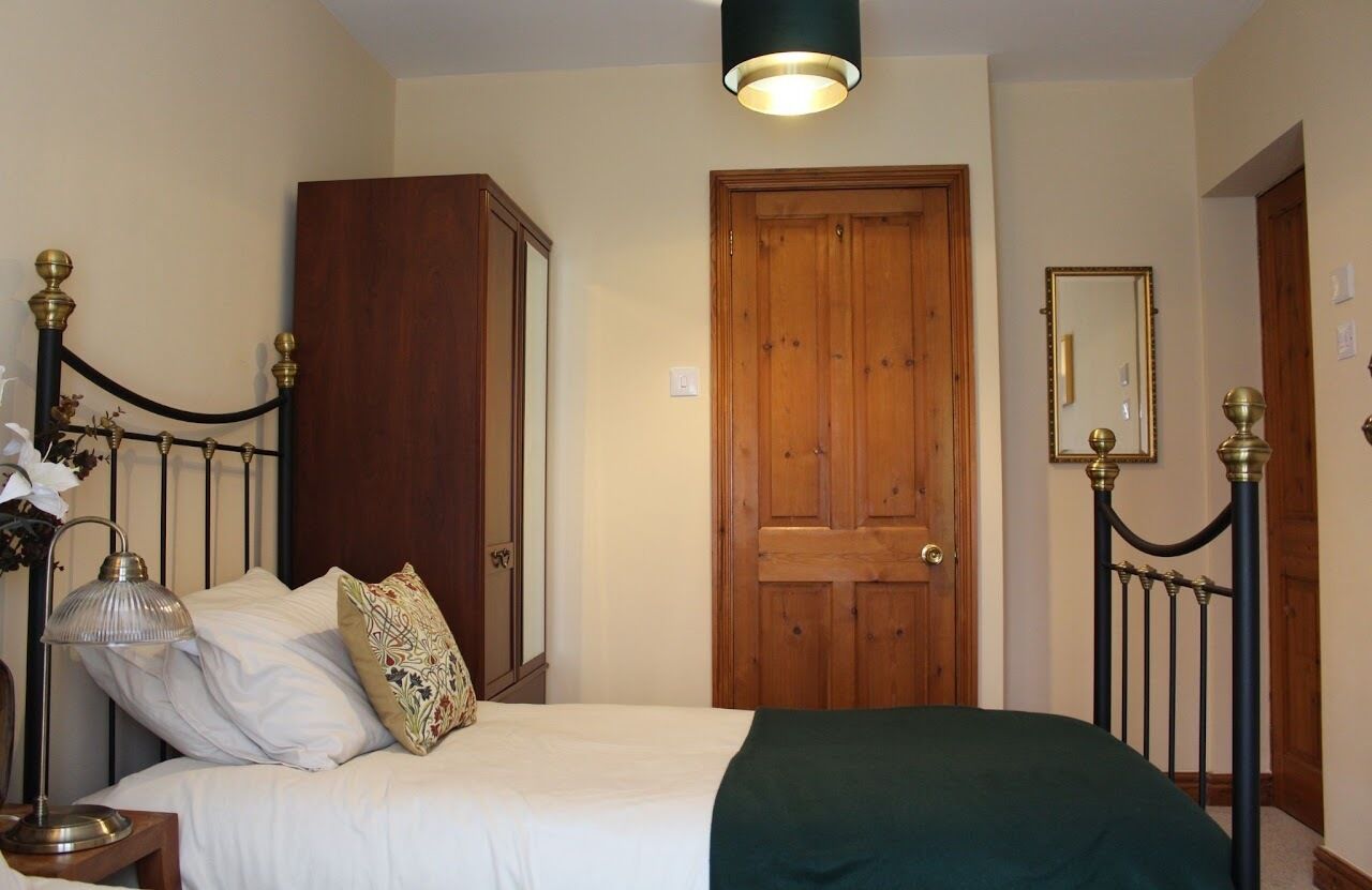 A bedroom with a bed, bedside lamp, and a wooden wardrobe.