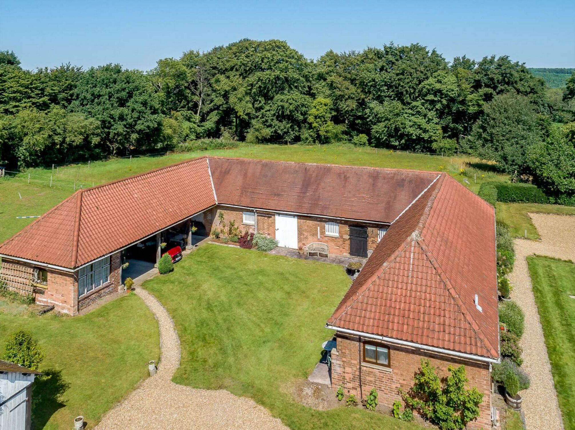 A large, L-shaped brick building with a red-tiled roof, a covered garage, and a well-maintained lawn.