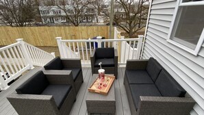 Eine Terrasse mit Korbmöbeln, darunter zwei Sofas und ein Couchtisch, mit einem Tablett mit Gläsern und Getränken.