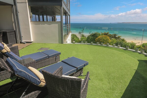 A patio with wicker furniture and a view of the ocean.