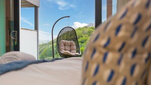 A bed with a view of a hanging chair and a building in the background. - Peninsula Apartment 2 (St Ives)