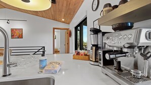 A modern kitchen with a built-in espresso machine, a sink, and a window overlooking a balcony. - Carriage House (Show Low)