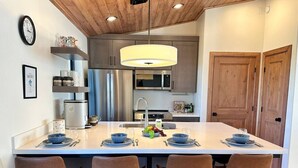 A modern kitchen with a central island, stainless steel appliances, and wooden ceiling. - Carriage House (Show Low)