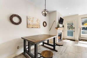 A dining area with a wooden table and chairs, a fireplace, and a view of a lake through a glass door. - Patio access to Keystone Lake & Gorgeous Views, Easy Access to Everything! (Keystone)