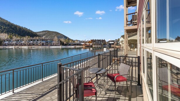 A deck with outdoor seating overlooking a river, surrounded by buildings and hills. - Patio access to Keystone Lake & Gorgeous Views, Easy Access to Everything! (Keystone)