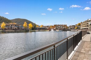 A riverside view with a wooden walkway, buildings with balconies, and autumn trees. - Patio access to Keystone Lake & Gorgeous Views, Easy Access to Everything! (Keystone)