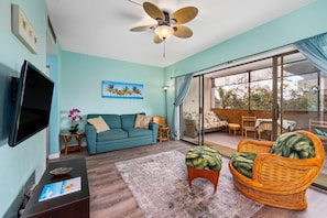 Relax in this stylish living room with a flat-screen TV, comfortable sofa, and wicker armchair.