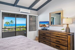 A bedroom with a large window, a bed, a TV, a dresser, and a lamp. - Wailea Ekolu #604 Ocean View! Walking Distance to Ulua Beach, Wifi, Full A/C (Wailea)