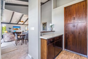 A modern kitchen with wooden cabinets, a dining area with a sofa and chairs, and a ceiling fan. - Wailea Ekolu #604 Ocean View! Walking Distance to Ulua Beach, Wifi, Full A/C (Wailea)