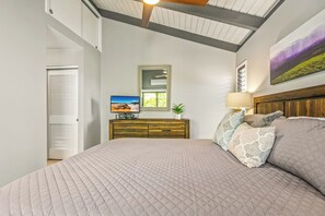 A bedroom with a large bed, a wooden dresser, a television, and a window with blinds. - Wailea Ekolu #604 Ocean View! Walking Distance to Ulua Beach, Wifi, Full A/C (Wailea)