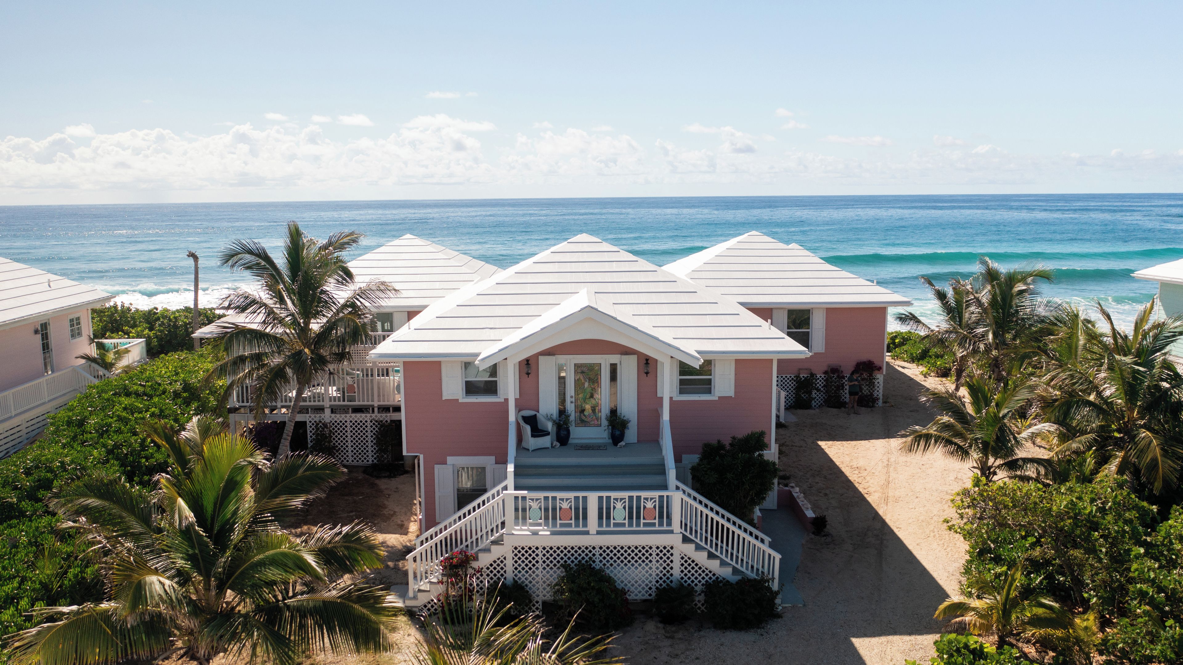 A beachfront house with a porch, a staircase, and a view of the ocean.
