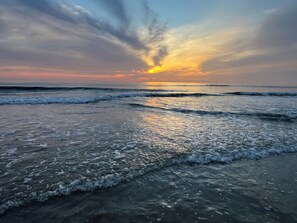 Una playa con olas y un atardecer.