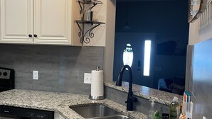A kitchen with granite countertops, stainless steel sinks, and white cabinetry. - Sunrose Cottage - Fresh & Clean - King Suite + free Wifi - Pet Friendly (Cibolo)