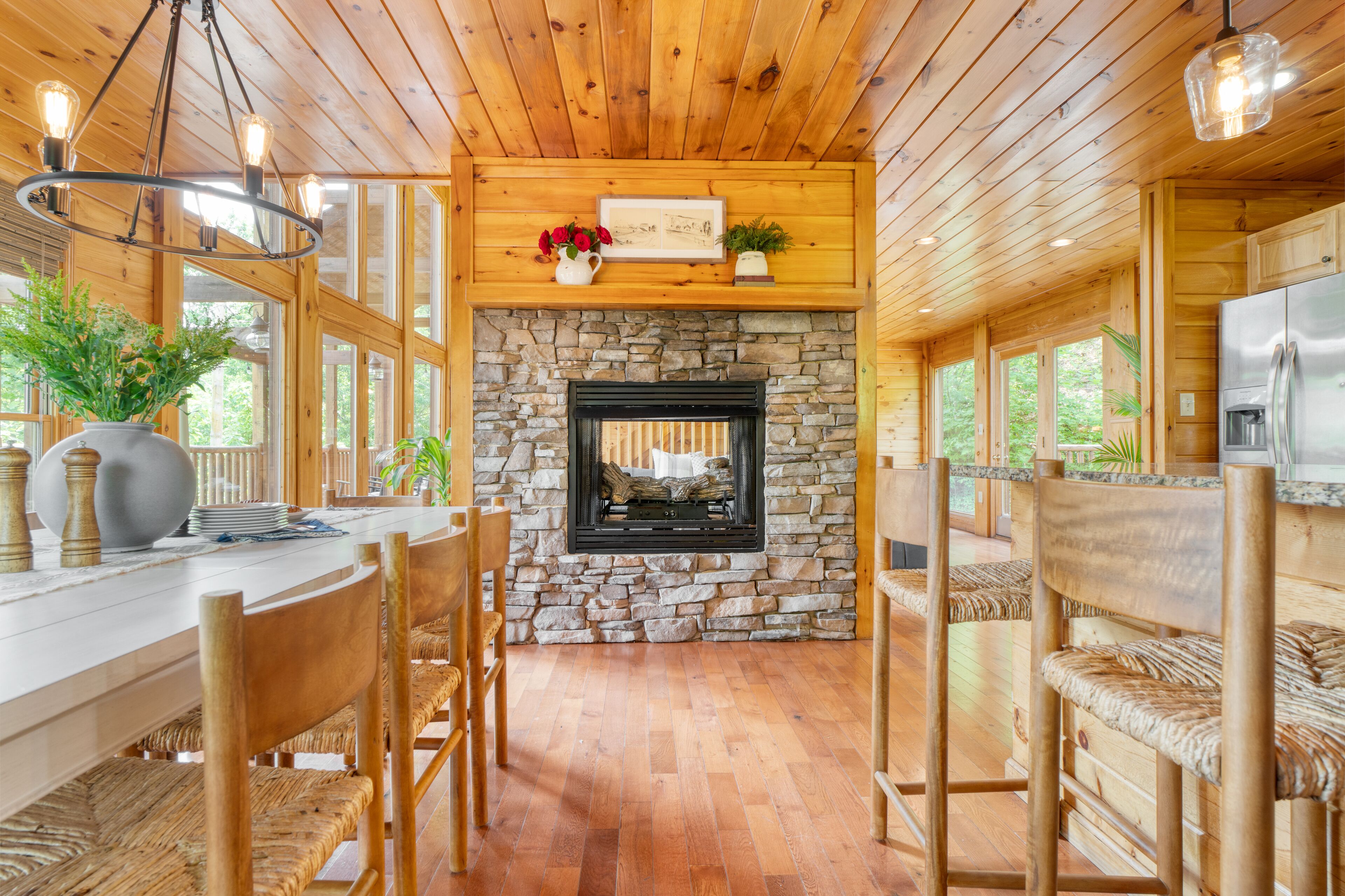 Un intérieur en bois avec une cheminée en pierre, une table à manger en bois, des chaises et un réfrigérateur.
