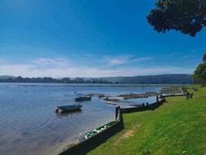 Vista sobre un llac amb barques, una zona verda i turons a la distància.