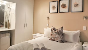 Una camera d'albergo con un letto, un comodino, uno specchio e opere d'arte appese al muro.