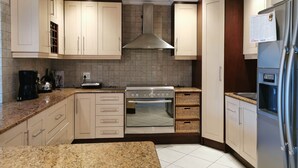 Una cucina moderna con armadietti chiari, un piano cottura in acciaio inossidabile, forno integrato e frigorifero.